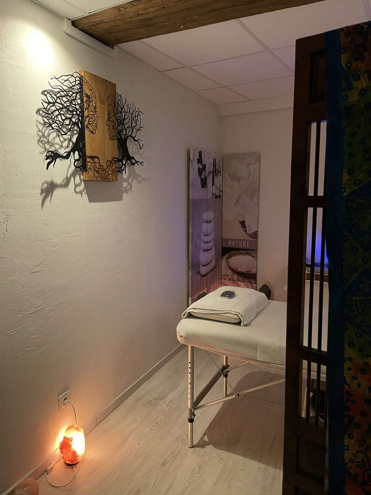 Cabine de soin d'Arhomeplus à Autun : table de massage, lampe de sel et tableau en bois