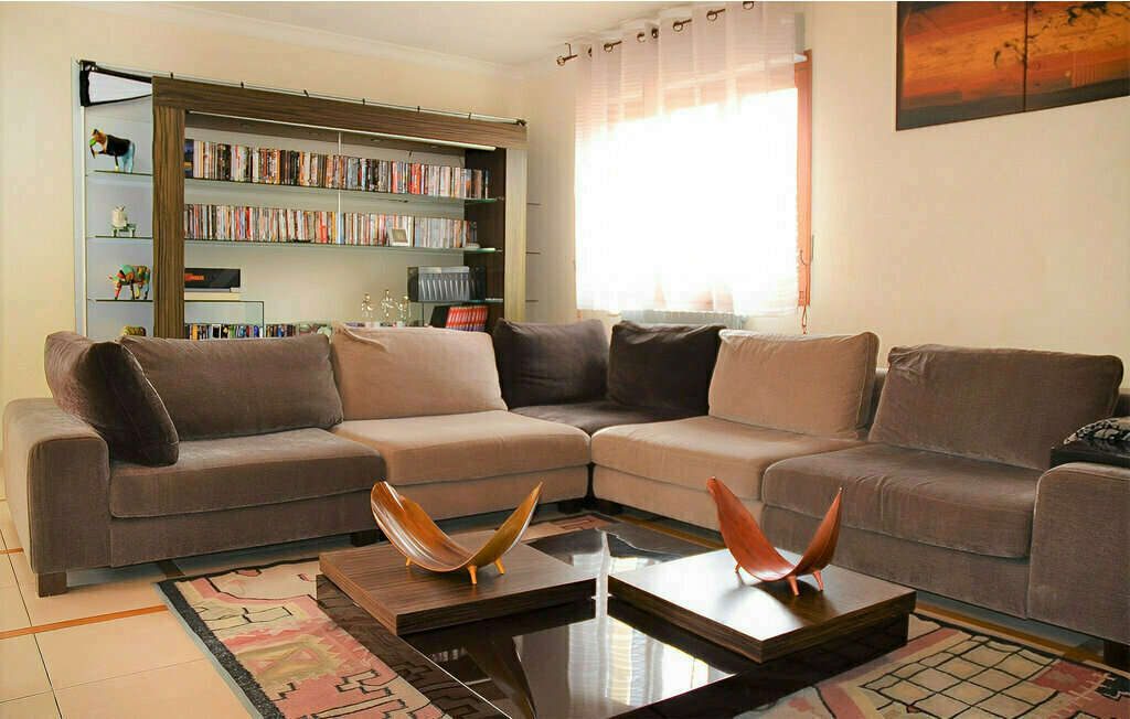 Salon du grand appartement Arhomeplus avec canapé d'angle et bibliothèque